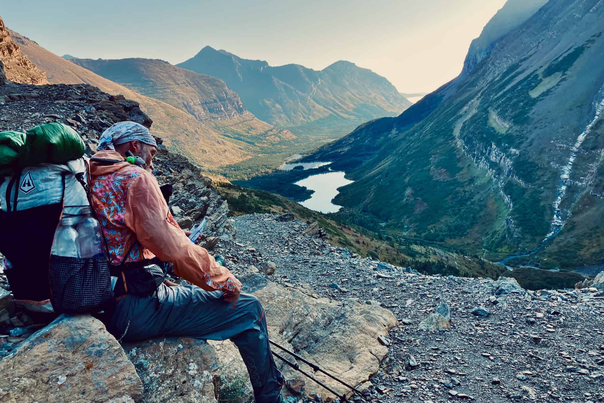 Boss resting high above a mountain valley with his backpack and trekking poles